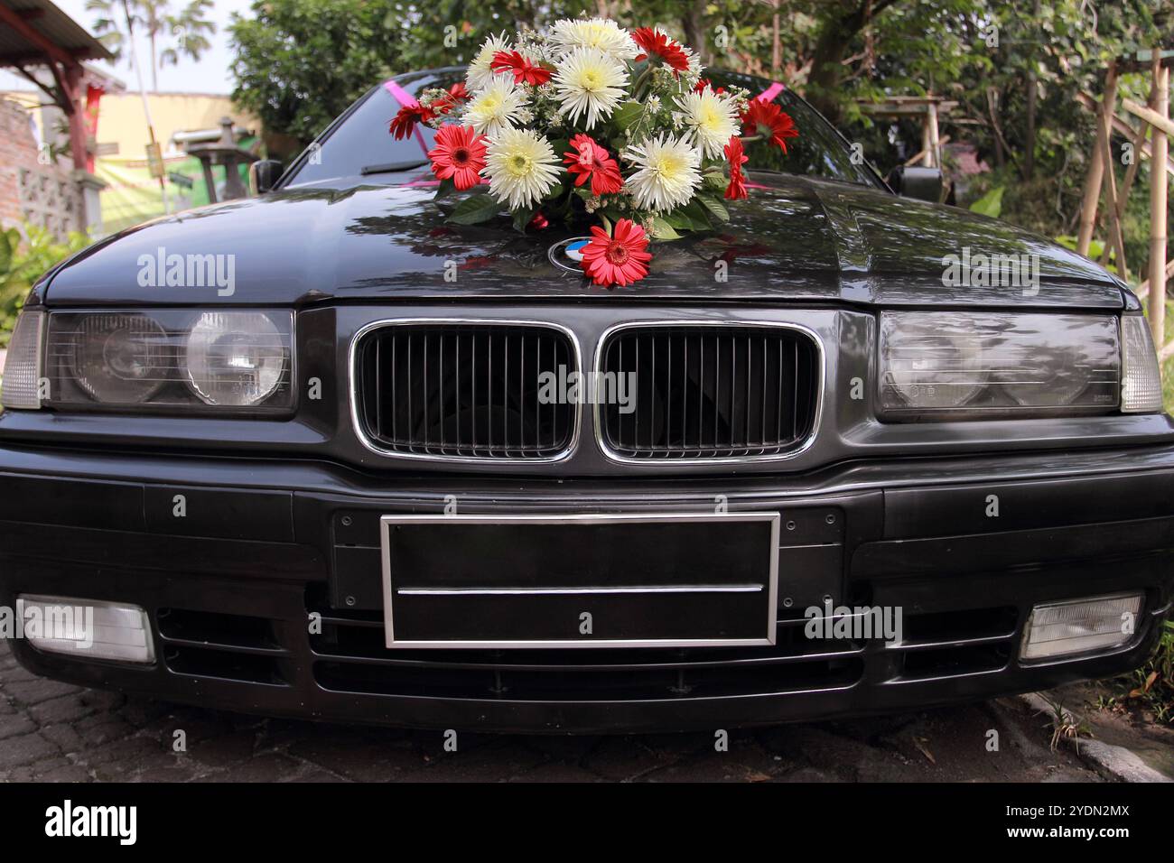 Die Scheinwerfer und der Kühlergrill einer klassischen Limousine sind mit einem Blumenstrauß verziert. Stockfoto