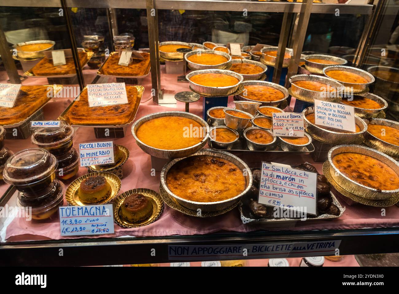 Reiskuchen (Torta di Riso) ist eine der Spezialitäten von Bologna. Die Ausstellung von Paolo Atti bietet eine Auswahl für den Festtag der Stadt saint San Lócca. Via degli Orefici, Bologna, Emilia-Romagna, Italien Stockfoto