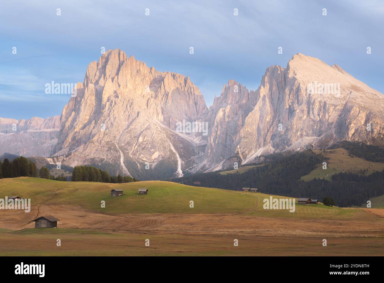 Idyllischer Vormittag- oder Abendblick auf die malerischen Wiesen der Seiser Alm mit urigen Hütten und die majestätischen Dolomiten in Südtirol, Italien. Stockfoto