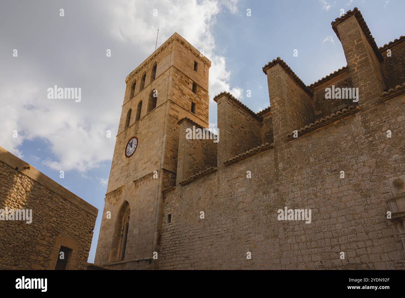 Majestätischer Steinturm der Burg Ibiza, ein historisches spanisches Wahrzeichen mit einer rustikalen Uhr, vor einem ruhigen mediterranen Himmel. Stockfoto
