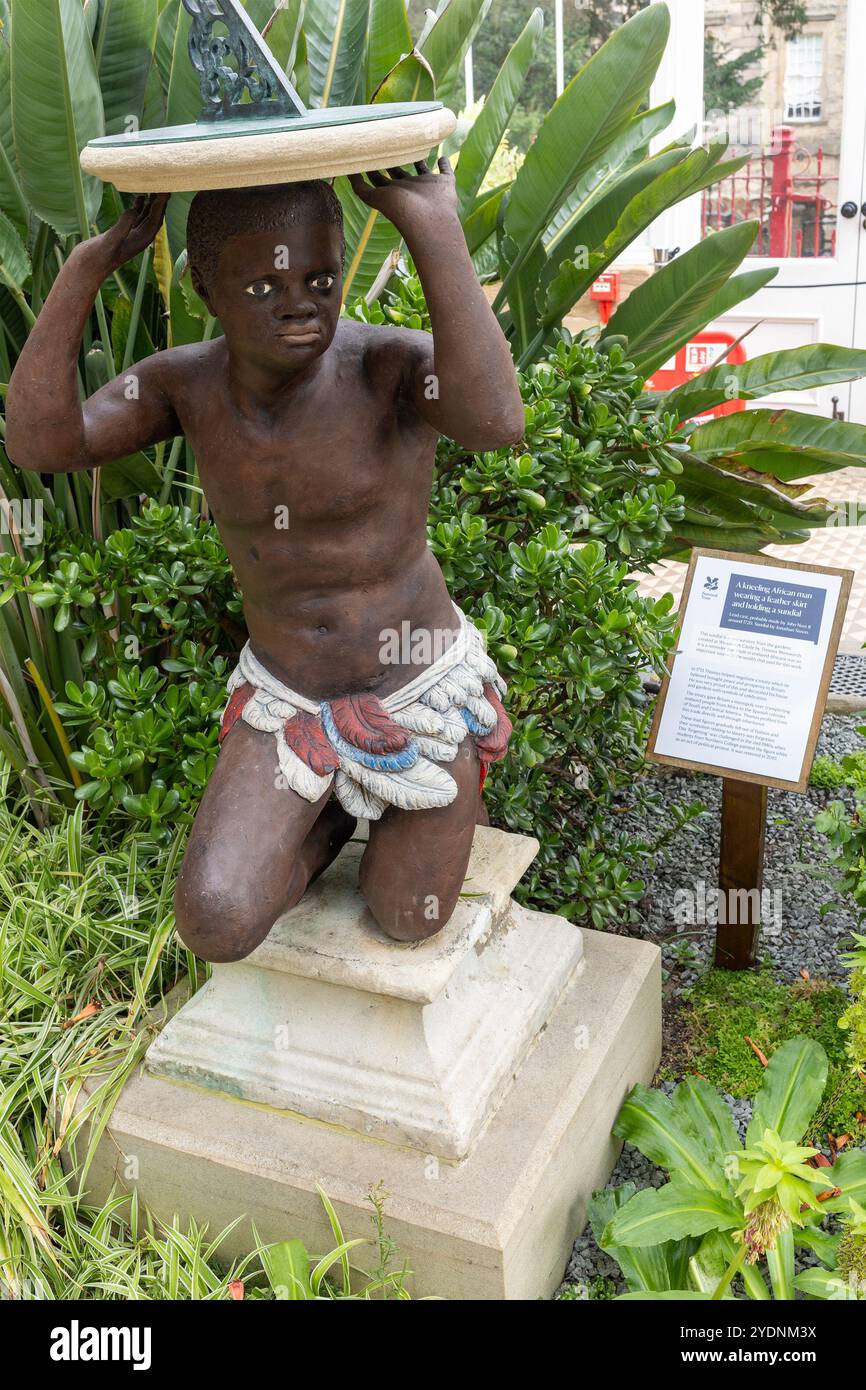 Eine kniende afrikanische Männerstatue in einem Federrock mit einer Sonnenuhr und einer Erklärung der Versklavung in Wentworth Castle Gardens, Yorkshire, England Stockfoto