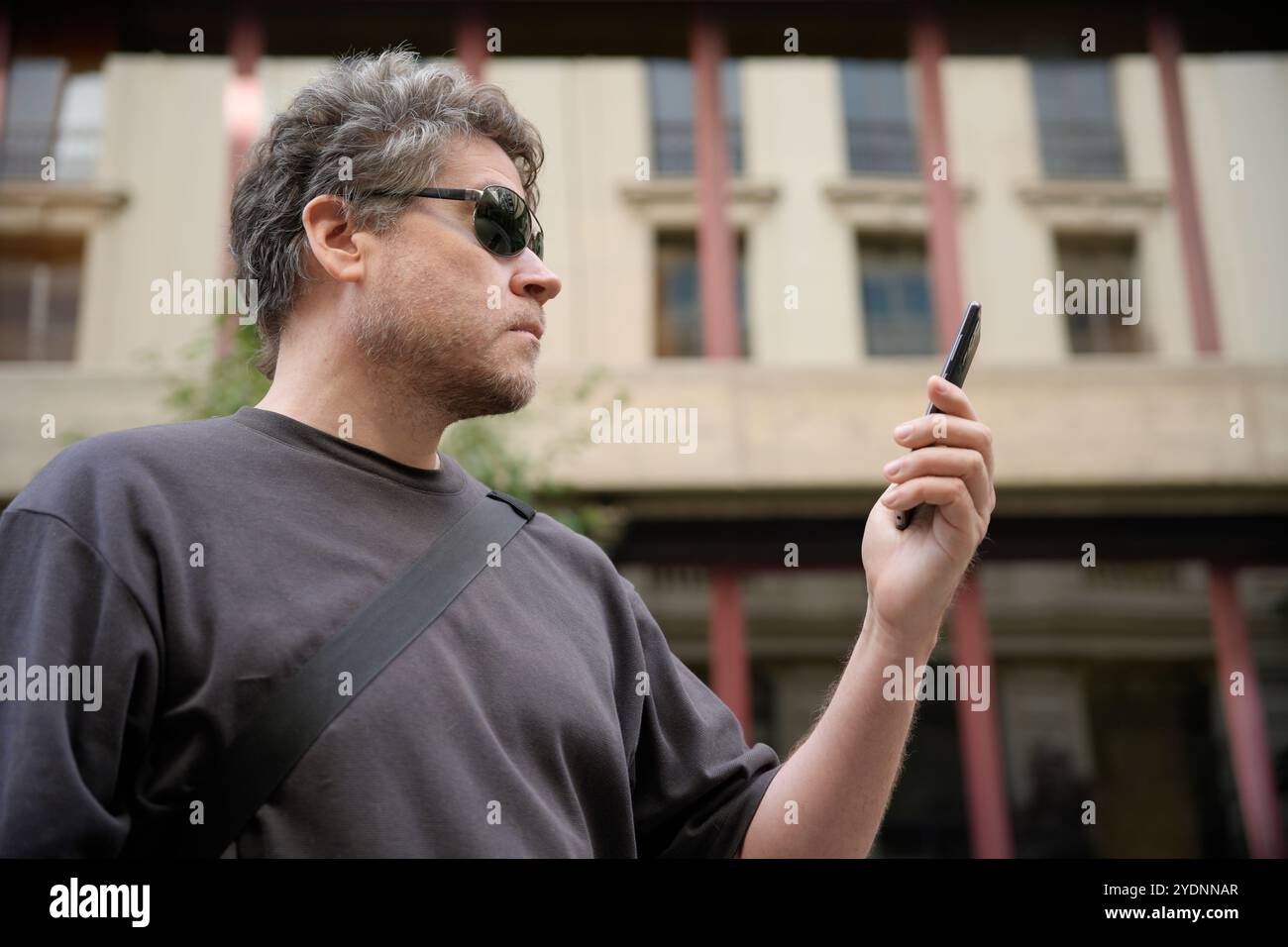 Ein kaukasischer Mann, der draußen auf den Handy-Bildschirm schaut Stockfoto