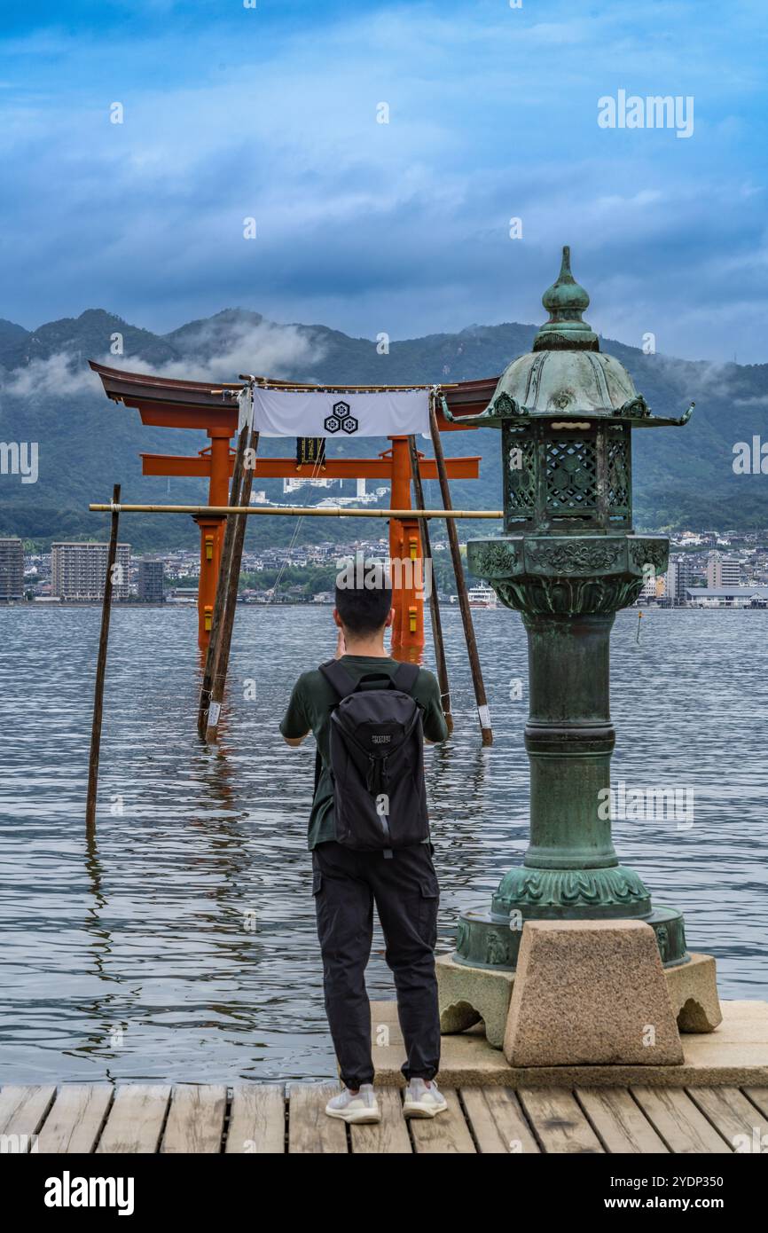 Hiroshima, Japan – 20. August 2024: Besucher fotografieren das schwimmende Tor von Otorii und die Laterne von Hitasaki am Itsukushima Jinja shinto-Schrein. Befindet Sich Stockfoto