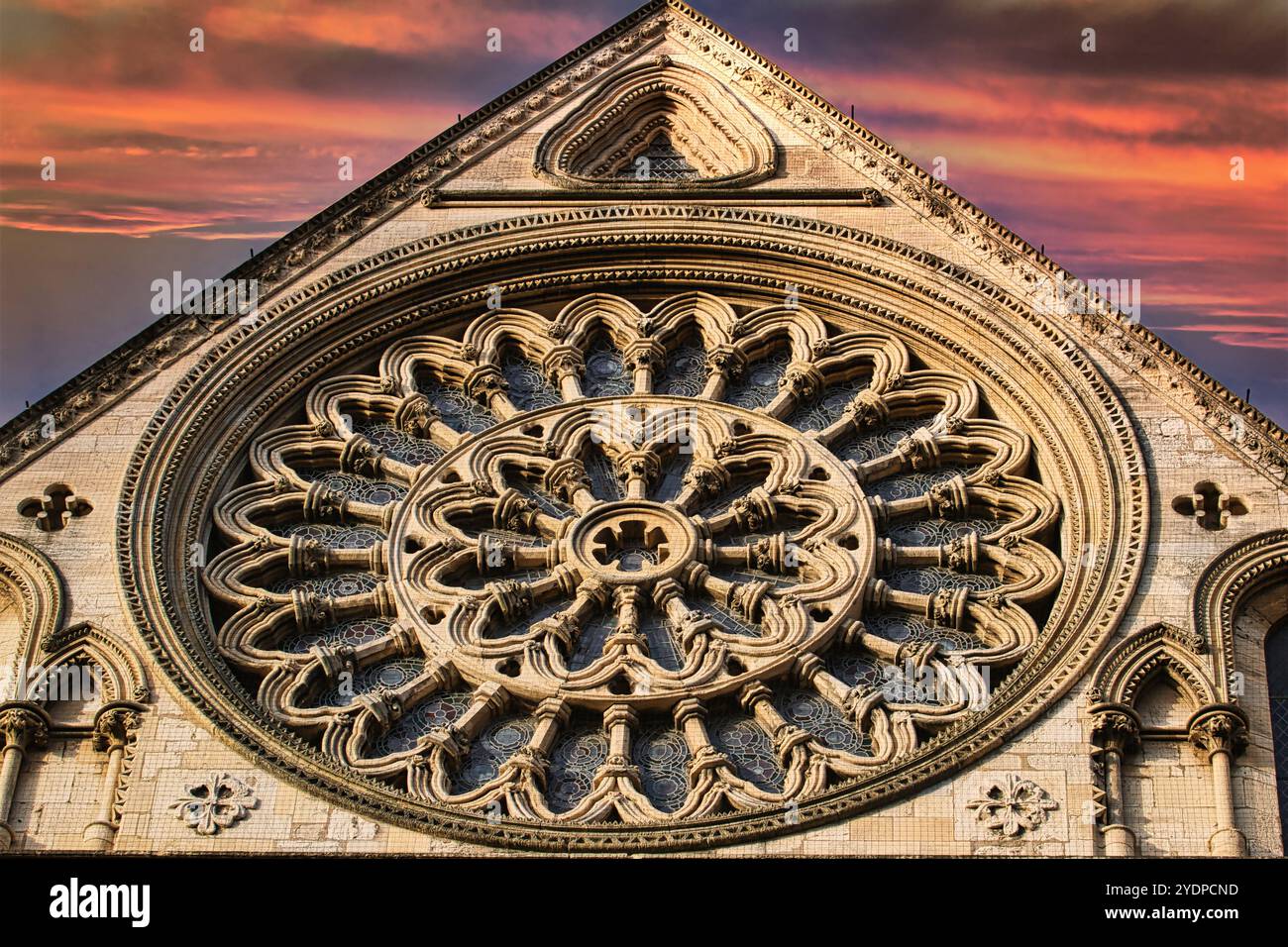 Ein großes, kreisförmiges Steinfenster, bekannt als Rosenfenster, ist in diesem Bild zu sehen. Das Fenster ist das Herzstück eines großen, hellen Gebäudes und Stockfoto