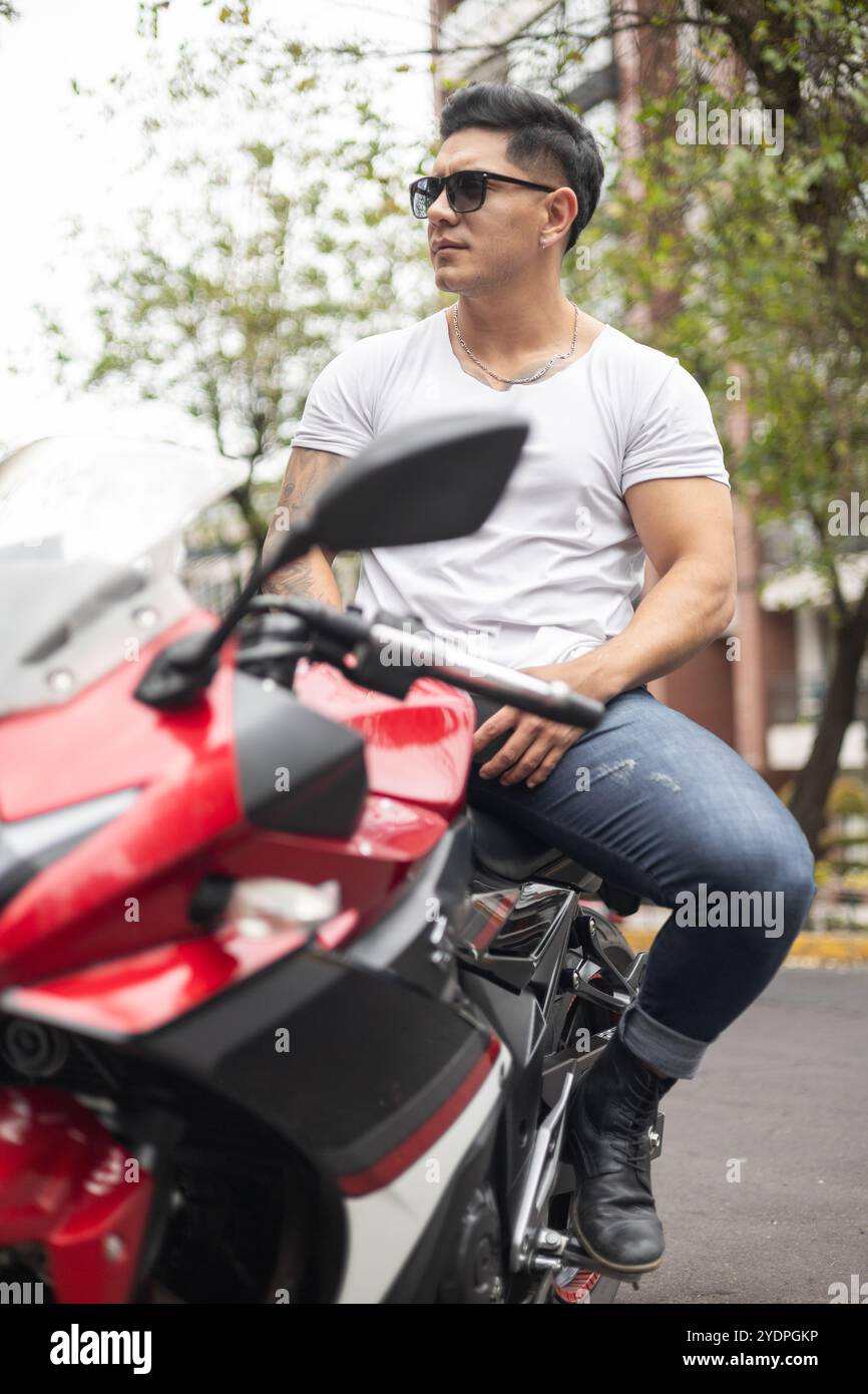 Männliches Modell, natürliche Schönheit eines lateinischen Mannes mit seinem Motorrad, Lebensstil und Transportmittel, lässige und coole Mode Stockfoto