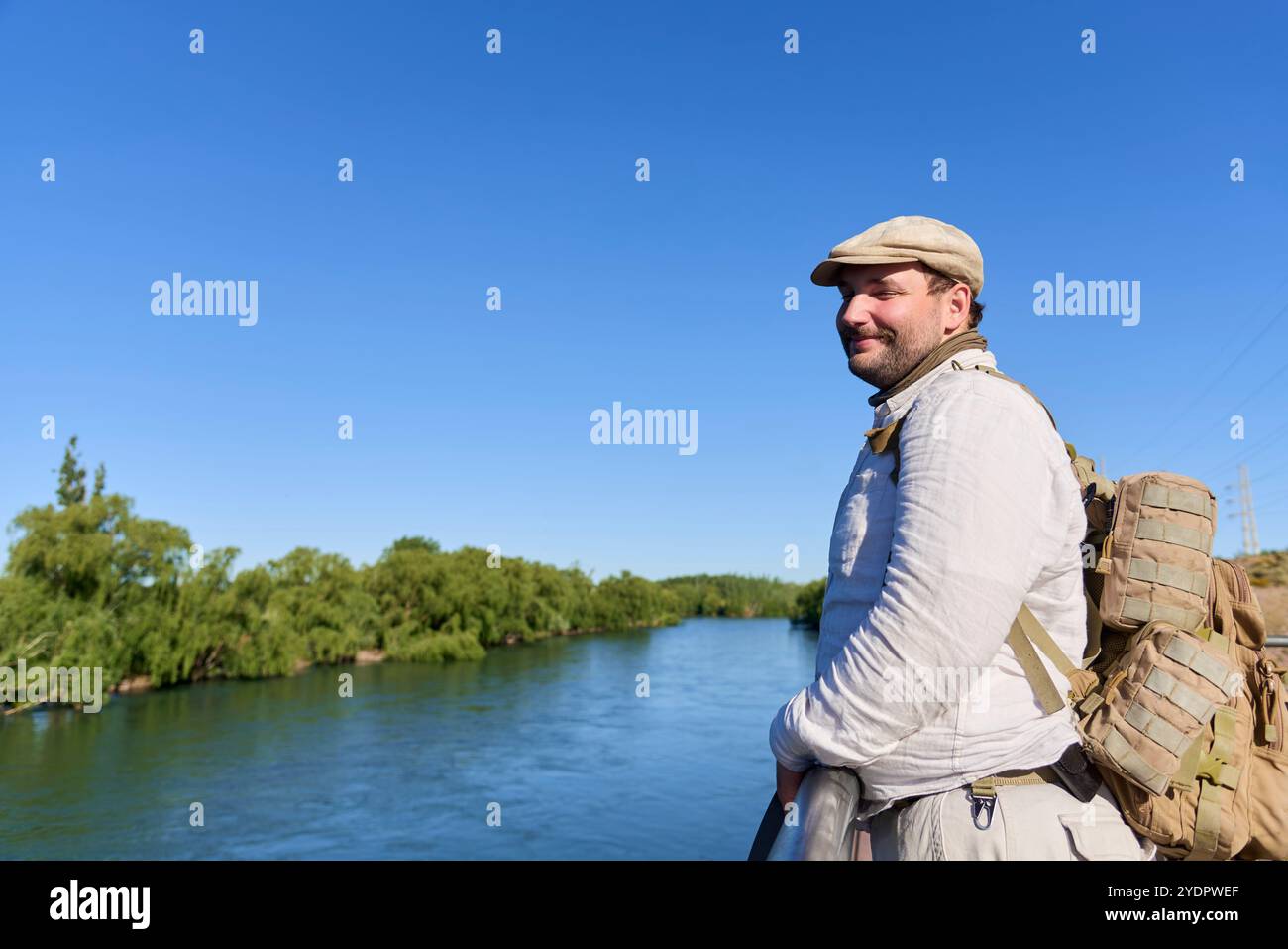 Glücklicher junger Mann, der an einem Aussichtspunkt über dem Neuquen River, Argentinien, lächelt. Verbindung mit der Natur in der Stadt im Frühling. Stockfoto