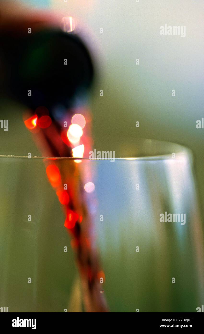 Rotwein wird aus einer Flasche in ein Glas gegossen Stockfoto