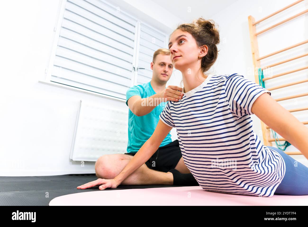 Frau mit Schmerzen im unteren Rücken in der Physiotherapie. Physiotherapeutin mit weiblicher Patientin, die Rückenbewegungsübungen macht. Stockfoto