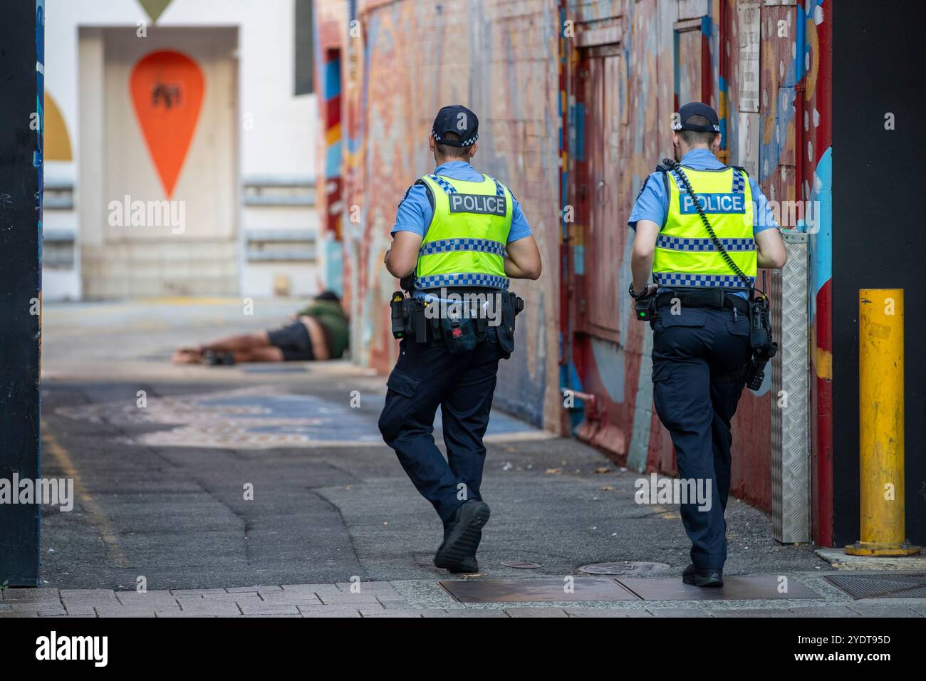 Perth Australien zwei Polizisten gehen auf eine Person zu, die in einer Graffiti-überdachten Gasse liegt. Stockfoto