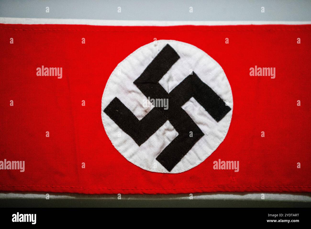 Dieses Bild zeigt eine Nazi-Flagge mit einem hellroten Hintergrund und einem weißen Kreis in der Mitte, der ein schwarzes Hakenkreuz enthält. Stockfoto