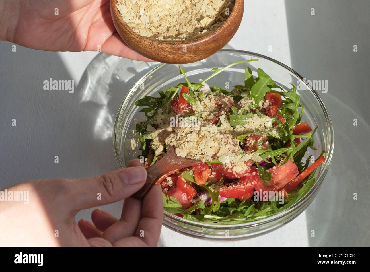 Einladender Salat, perfekt für warme Sommerabende, mit erfrischendem Rucola, Tomaten, abgerundet mit einem Stäuben aromatischer Hefe. Leicht und Stockfoto