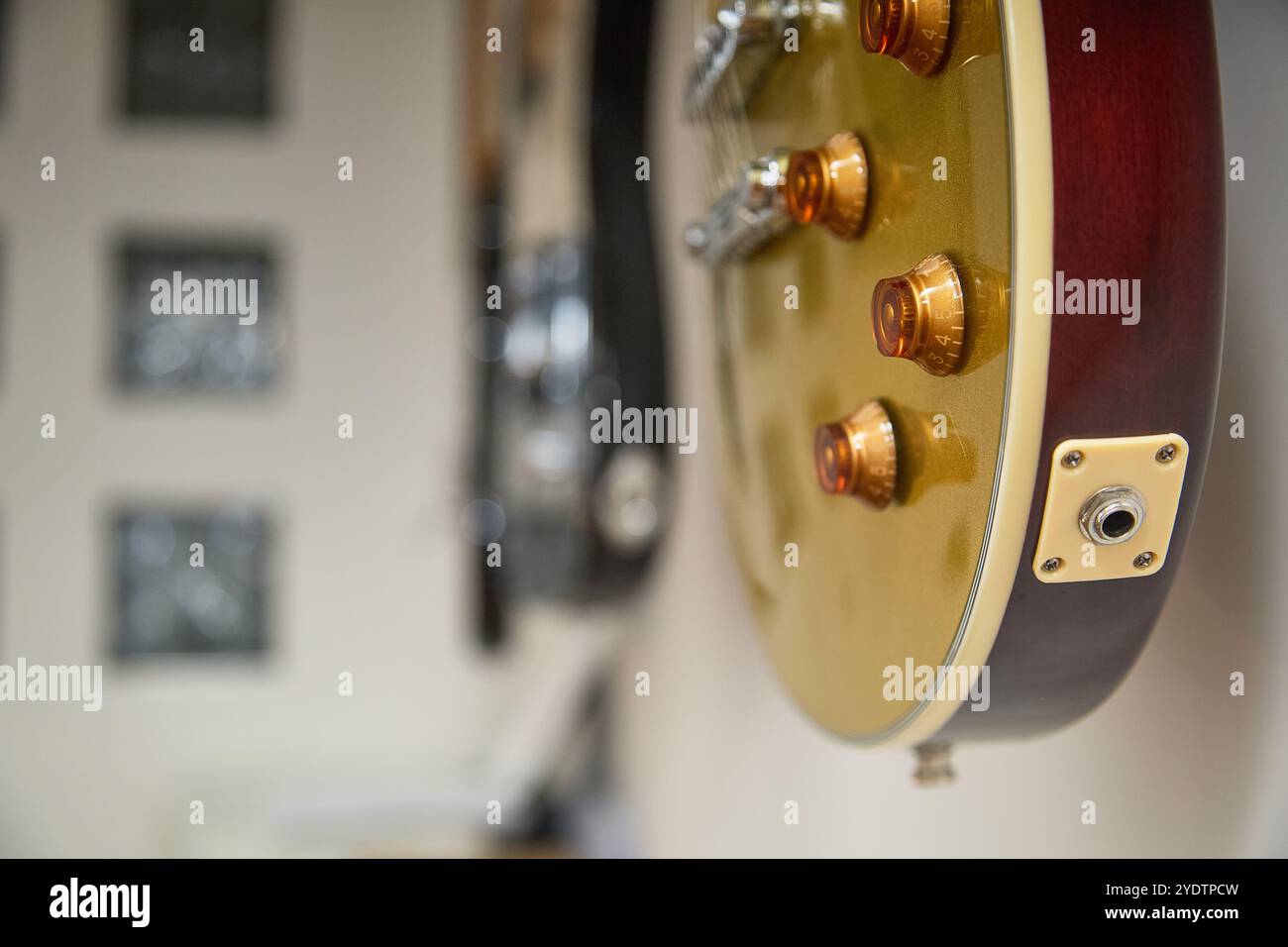 Goldene Vintage-E-Gitarre hängt an einer Wand, Seitenaufnahme mit Unschärfe Stockfoto