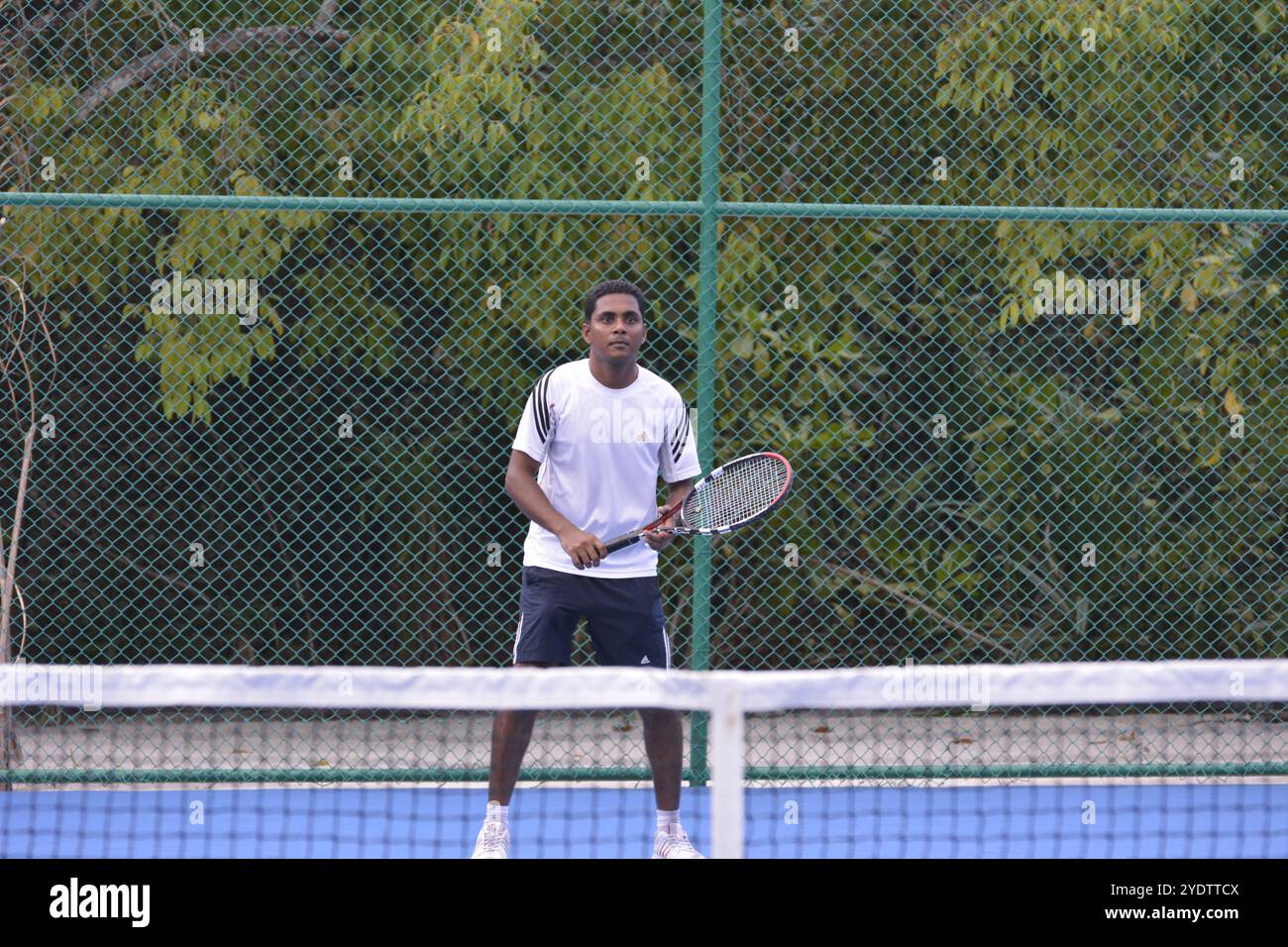 Randheli, Malediven - 24. Februar 2014: Ein asiatischer Indianer spielt Tennis auf einem tropisch blauen Tennisplatz. Stockfoto