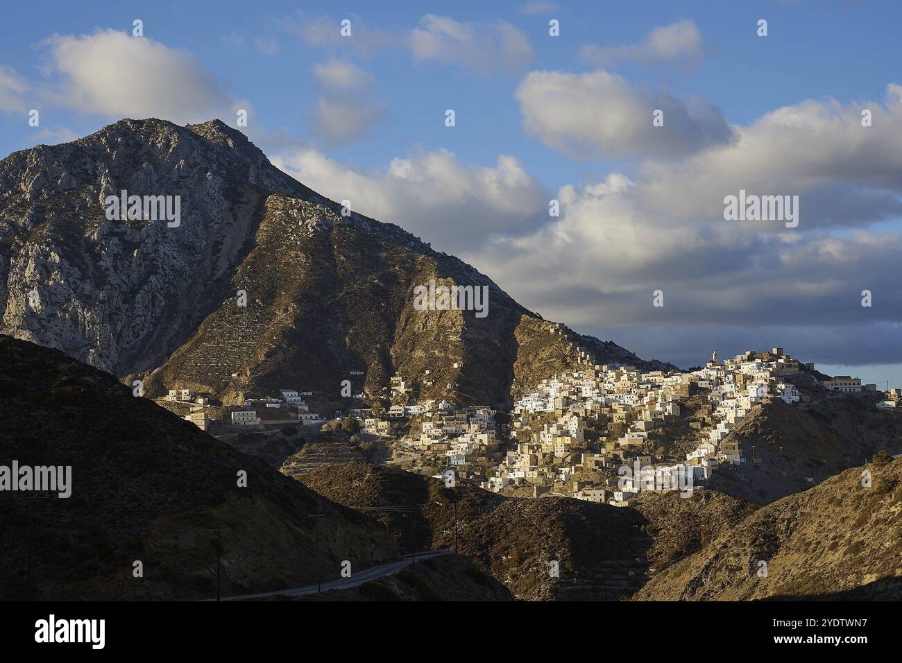 Ein aufsteigendes Dorf auf einem Bergrücken, von der Sonne beleuchtet, vor einem bewölkten Himmel, farbenfrohe Bergdorf, Morgenlicht, Olymbos, Karpathos, Dod Stockfoto