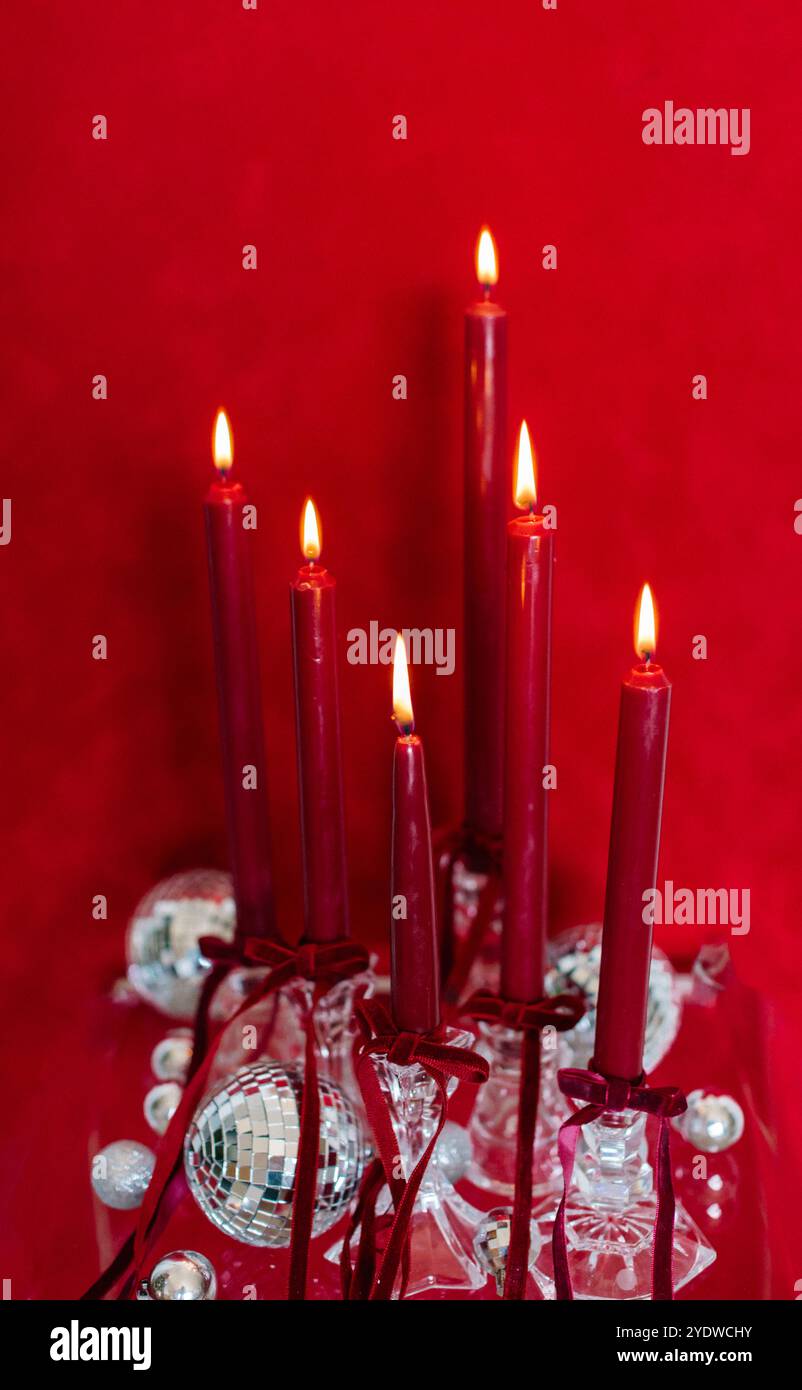Rote Kerzen mit Discokugeln vor festlicher roter Kulisse Stockfoto