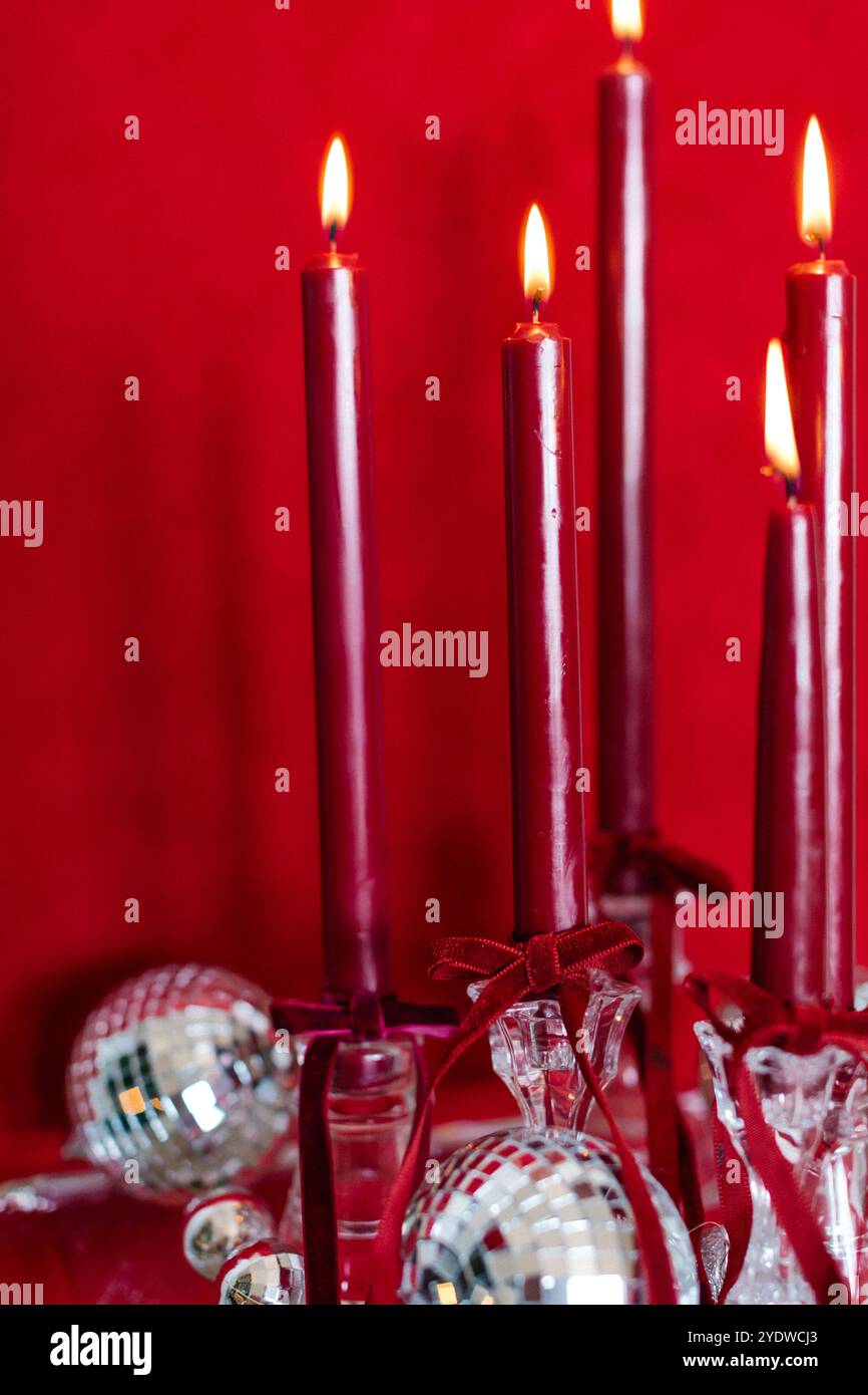 Rote Kerzen mit Discokugeln vor festlicher roter Kulisse Stockfoto