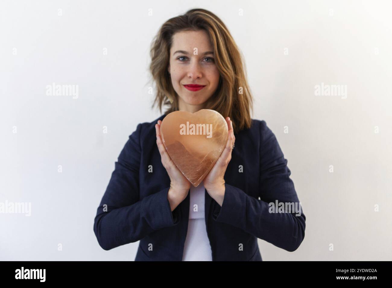 Eine befähigte Frau genießt Erfolg, hält ein heiliges Herz über der Brust, aus Steinmineralien geschnitzt, für Meditation und gesundheitliche Vorteile verwendet Stockfoto