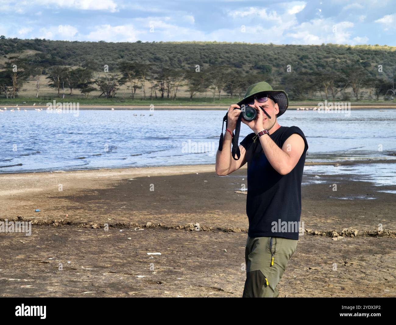 Ein Fotograf mit grünem Hut fotografiert die Savanne auf dem Hintergrund des Lake Nakuru in Kenia. Das Konzept einer afrikanischen Safari in Afrika. A p Stockfoto