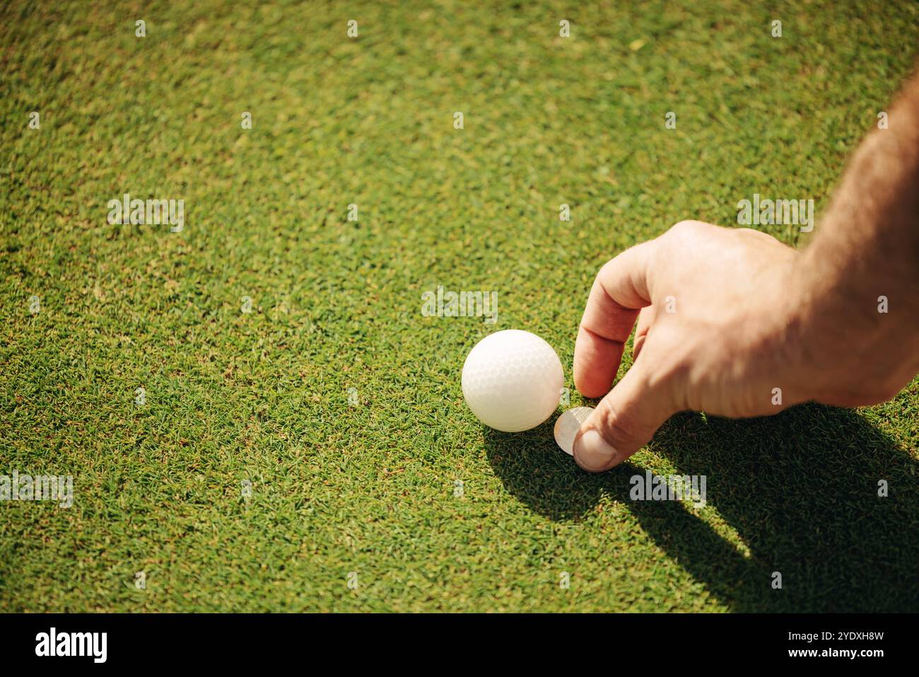 Ein Mann, der einen Golfball platziert und den Marker auf dem Grün bewegt, wobei er sich darauf konzentriert, den perfekten Schuss auf dem Golfplatz zu schaffen. Stockfoto