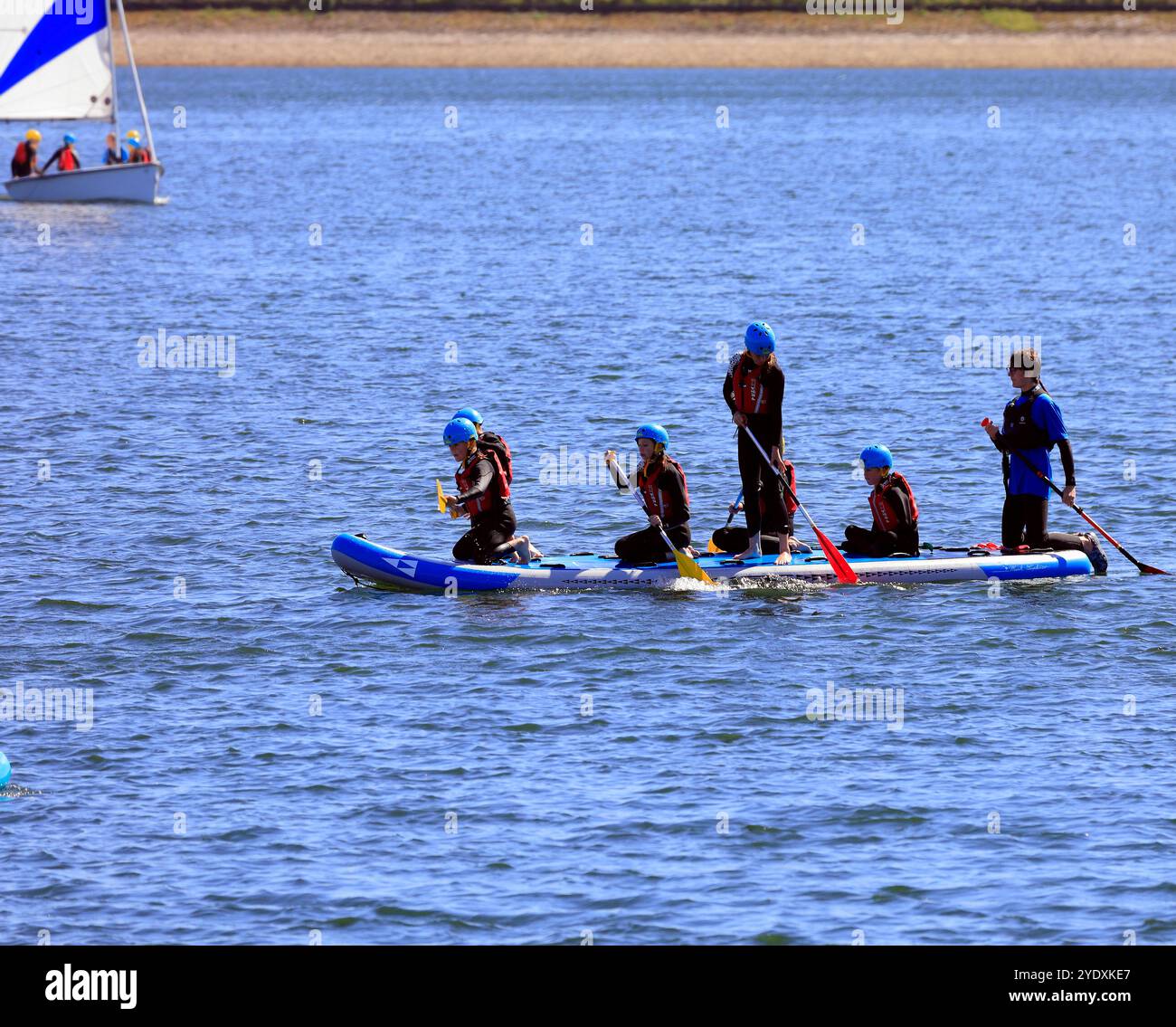 Paddelboarding und Segelunterricht für Jugendliche in Sicherheitsausrüstung auf einem großen Paddelbrett, Lisvane & Llanishen Stauseen, Sommer 2024 Stockfoto