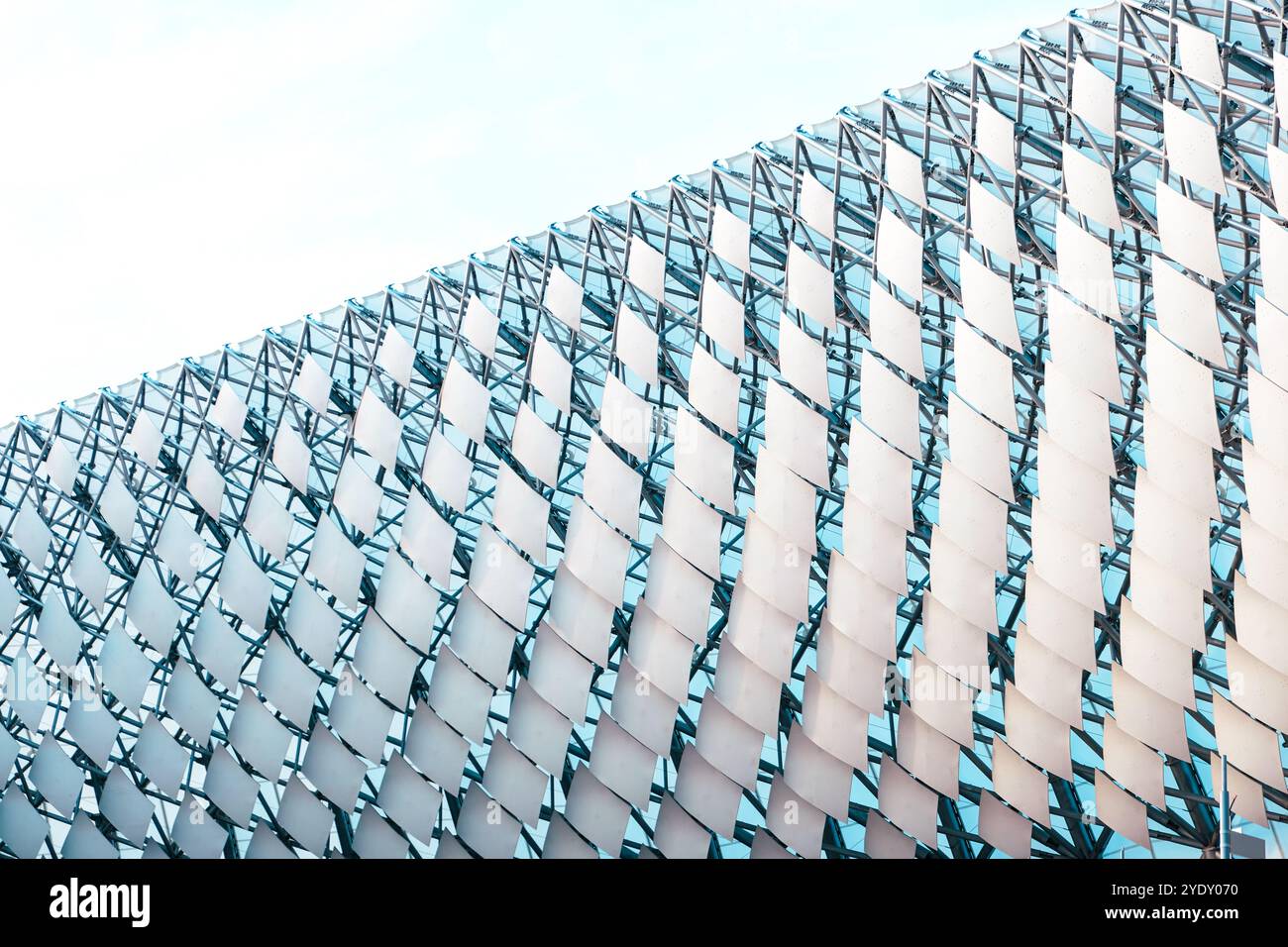 Ein markantes Gitterdesign bildet die Fassade eines kulturellen Veranstaltungsortes und zeigt einen modernen architektonischen Stil vor einem hellen Himmel. Die Struktur betont c Stockfoto