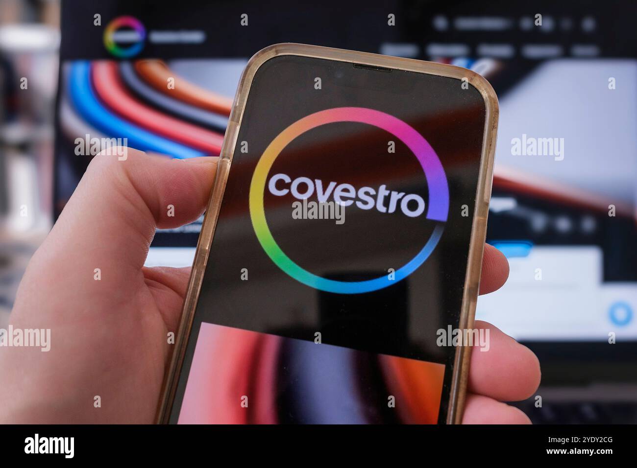 Hand mit einem Mobiltelefon, auf dem das Covestro-Logo zu sehen ist Stockfoto