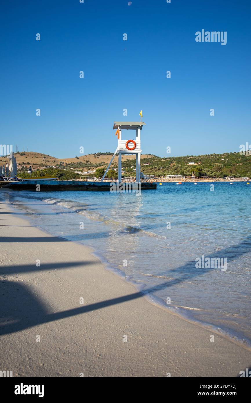 Vertikale Landschaft von Sandy Shore und Rettungsschwimmerturm in Ksamil. Sonniger Morgen am Strand mit dem Ionischen Meer an der albanischen Riviera. Stockfoto