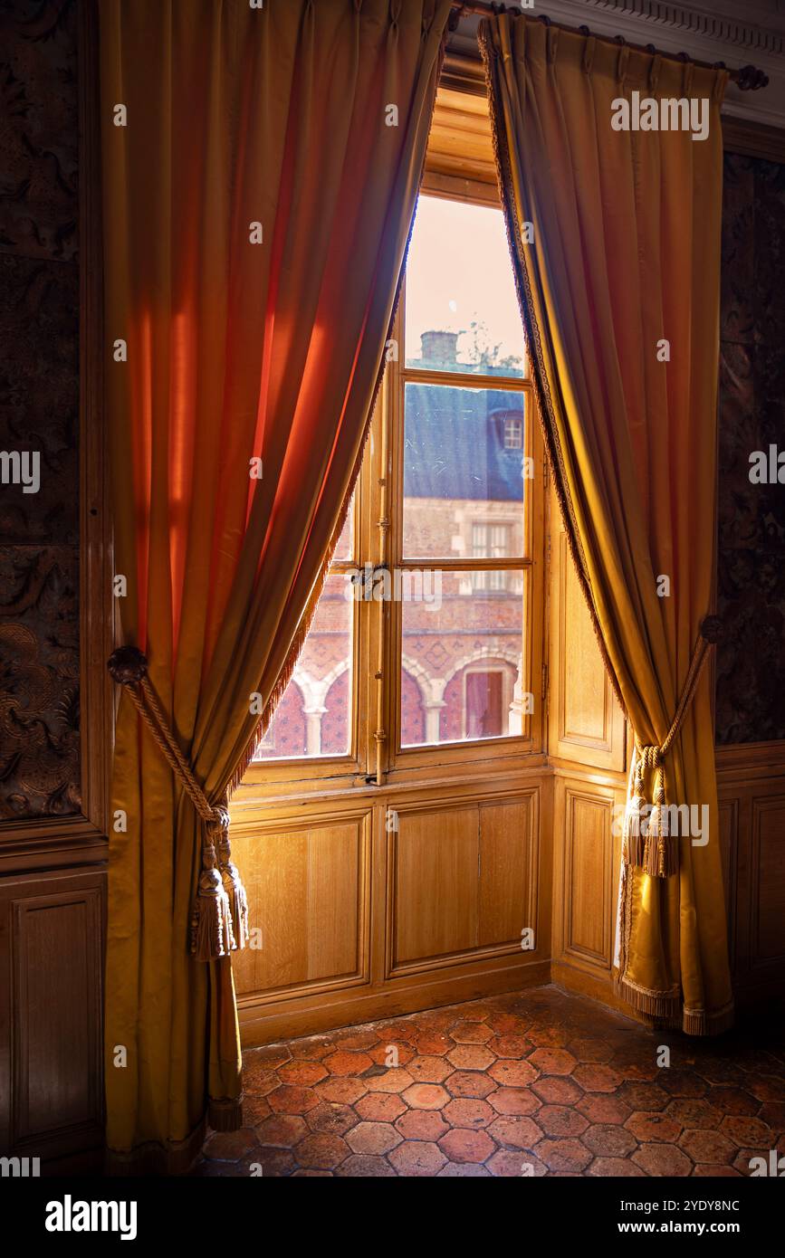 Abend- oder Morgensonne, die durch rote Vorhänge in einen Raum im alten Stil eindringt Stockfoto
