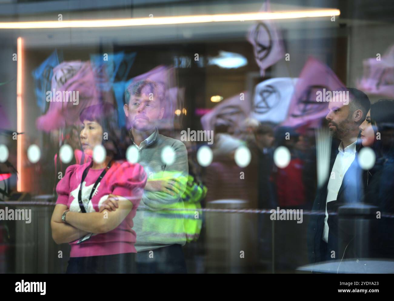 London, England, Großbritannien. Oktober 2024. Arbeiter im Walkie-Talkie-Gebäude, in dem die Tokio Marine Versicherungsgesellschaft untergebracht ist, beobachten, wie Demonstranten vor ihren XR-Flaggen im Glas dämonisieren. Extinction Rebellion (XR) spazieren Sie durch die City of London, halten Sie an und demonstrieren Sie vor den Büros von Versicherungsunternehmen, die trotz der Warnungen vor einer Klimakrise von Wissenschaftlern weiterhin Unternehmen für fossile Brennstoffe versichern. Die Demonstranten glauben, wenn die Versicherungsgesellschaften ihre Beteiligung an diesen Unternehmen beenden würden, würden sie es schwer tun, weiter zu bauen. Die Aktion ist die erste von A Stockfoto