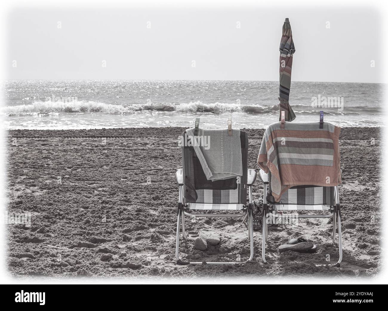 Zwei Liegestühle nebeneinander an einem leeren Strand in Vintage-Farben, die Feiertage und die Liebe zu einem älteren Paar im Ruhestand repräsentieren Stockfoto