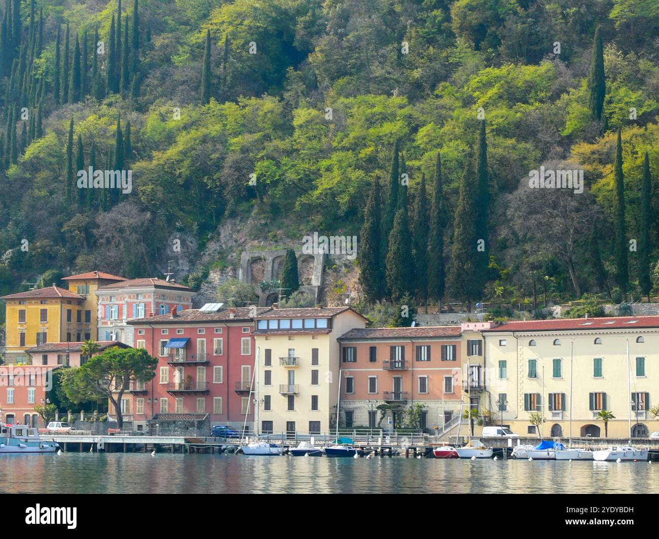 Blick auf die Gemeinde Toscolano Maderno vom Gardasee. Im Hintergrund ein steiler Hang mit vielen Zypressen. Stockfoto