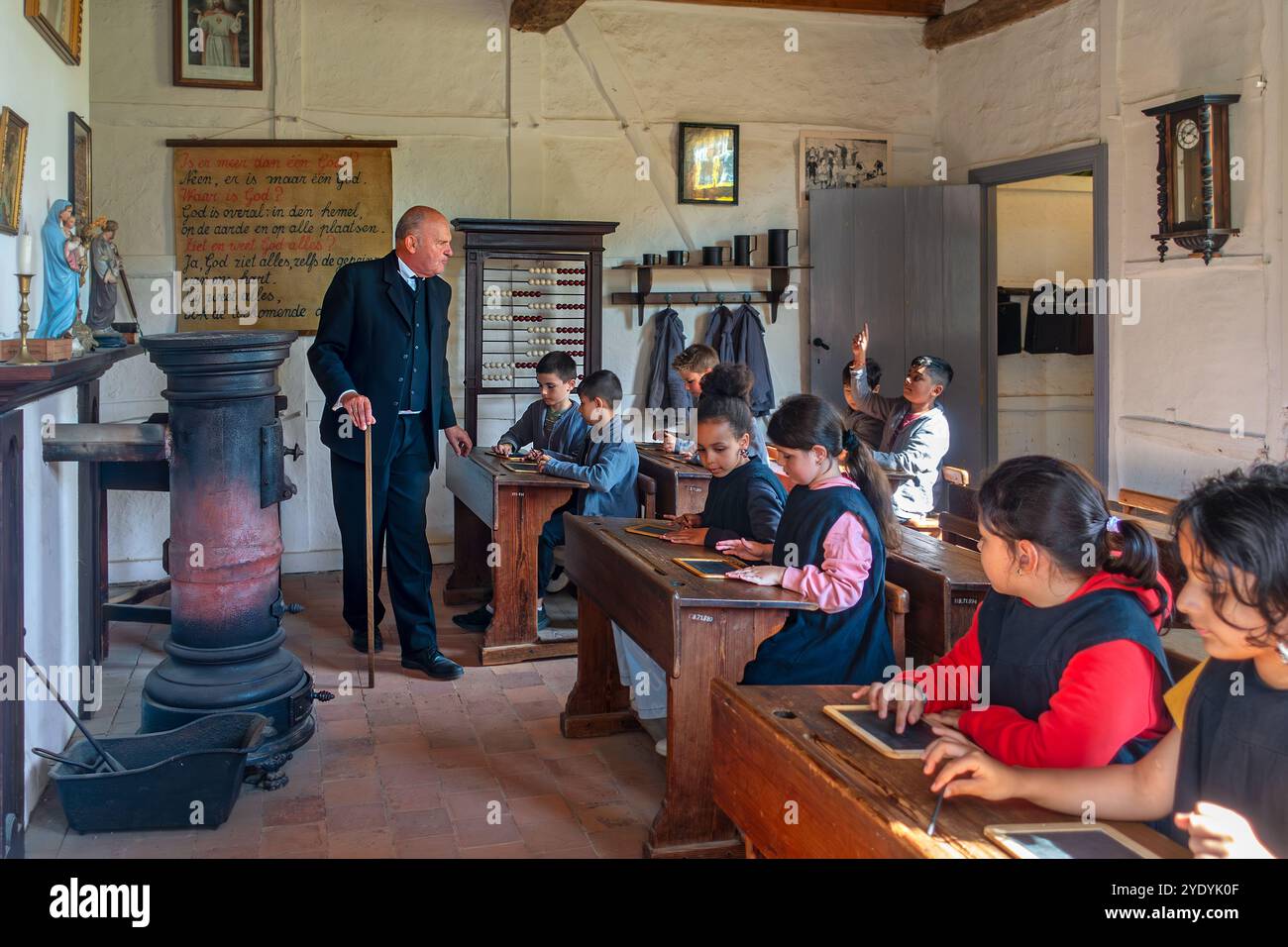 Schauspieler, der alte Schullehrer spielt und Schulkinder in der Klasse des 19. Jahrhunderts im Freilichtmuseum Bokrijk, Limburg, Flandern, Belgien unterrichtet Stockfoto