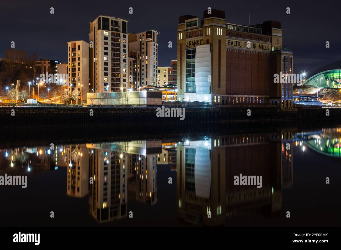 Neu erbaute Wohngebäude und die umgebaute Balted Mill spiegeln sich nachts in Gateshead im Wasser des Flusses Tyne wider. Stockfoto