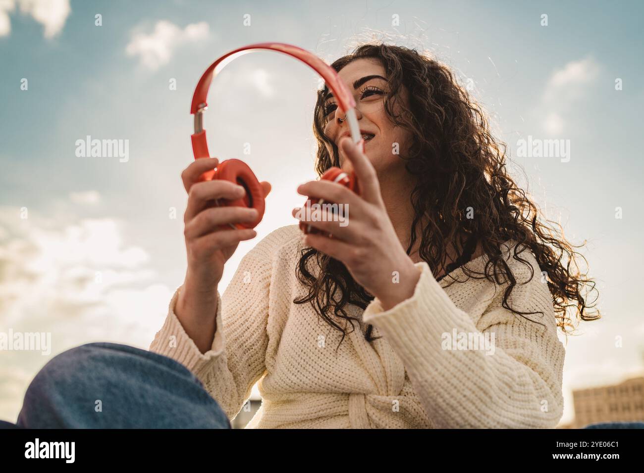 Schöne, vielfältige Frau mit natürlichen lockigen Haaren und Zahnspangen, die Musik im Freien genießen. Modernes Lifestyle-Porträt, das authentische Jugendkultur und Selbstbewusstsein zeigt Stockfoto