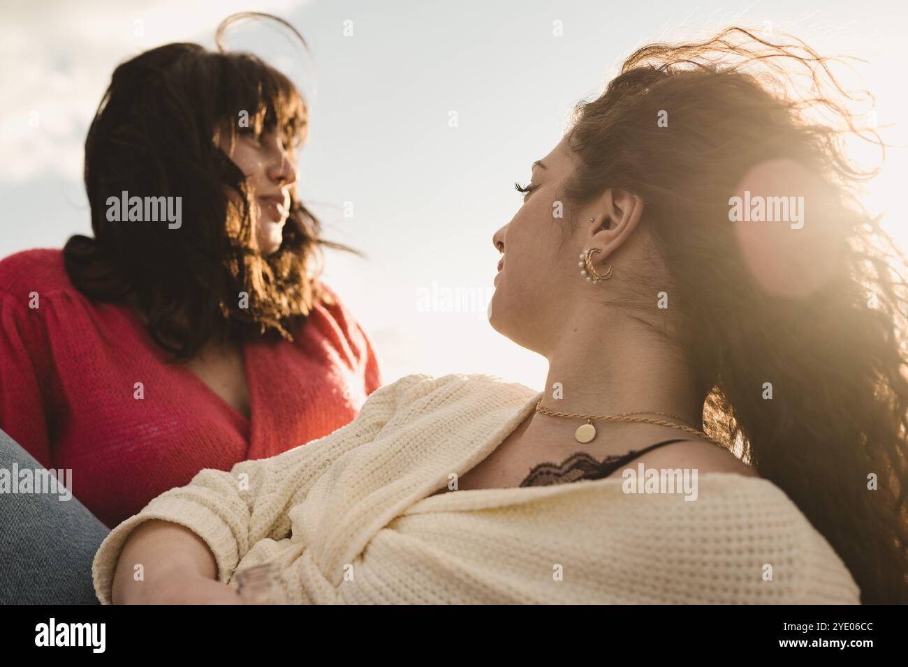 Natürliches Porträt von Freunden der Generation Z, die sich zur goldenen Stunde im Freien entspannen. Ein zeitgenössisches Lifestyle-Bild, das verschiedene Frauen zeigt, die eine echte Verbindung teilen und Stockfoto