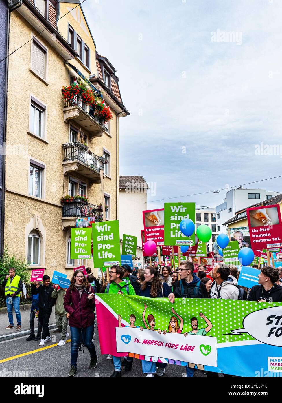 Zürich, Schweiz, 14. September 2024: Von einem Balkon eines Wohnhauses gießt ein Mann eine Flüssigkeit auf die Teilnehmer des Marsches für das Leben. (Foto Stockfoto