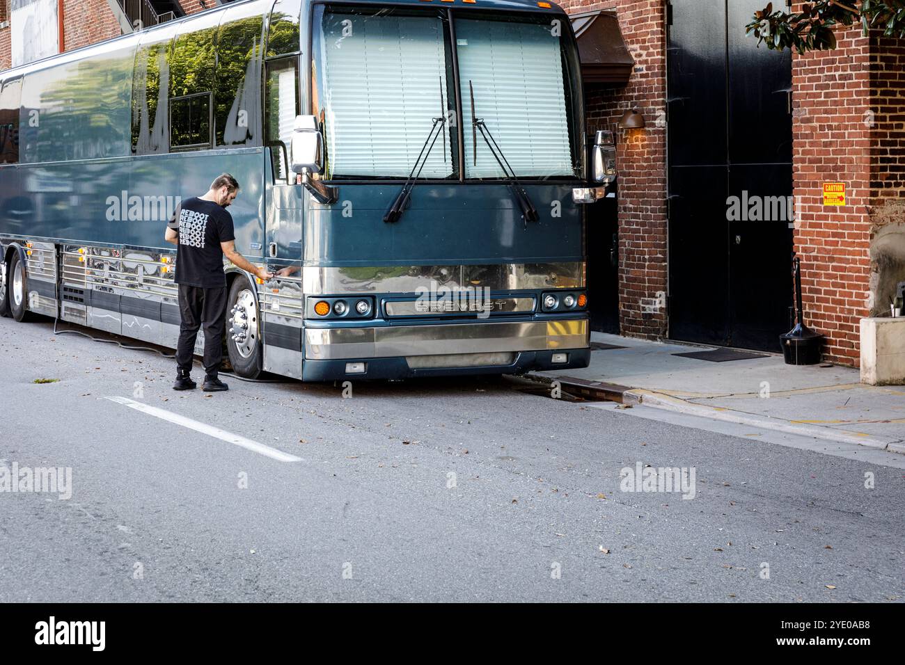 Knoxville, TN, USA-21 Sept. 2024: Mann schließt ein Ablagefach eines Prevost Tourbusses ab, an der Seite des Bijou Theaters. Stockfoto
