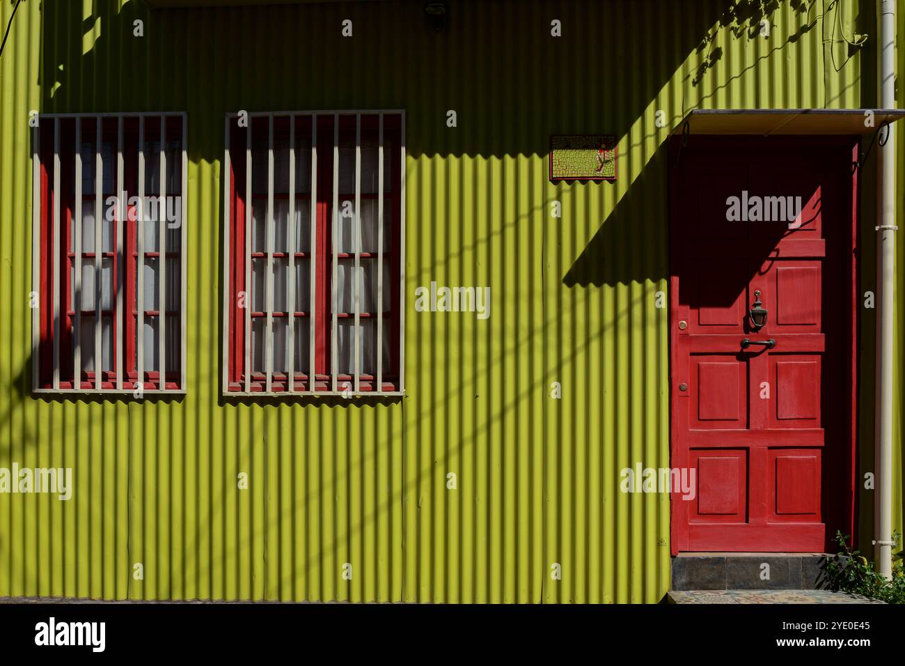 Fassade des farbenfrohen traditionellen Hauses von Valparaiso mit roter Holztür und fleckiger grüner Wand in Cerro Artilleria, Chile UNESCO-Weltkulturerbe Stadt of Stockfoto