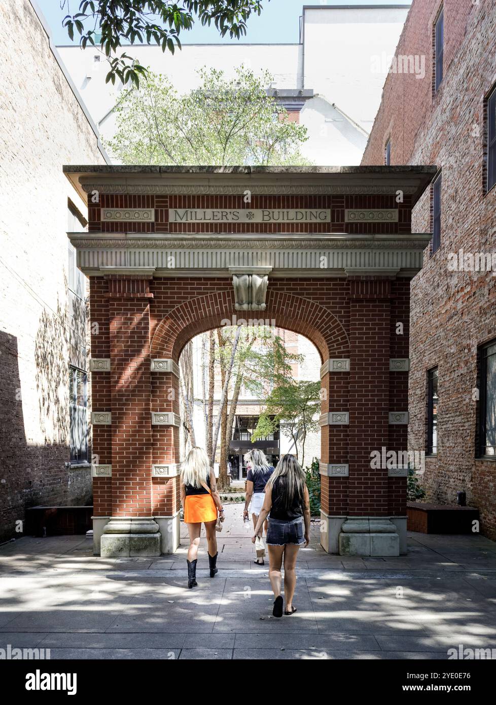 Knoxville, TN, USA-21 Sept. 2024: Drei junge Frauen mit langen silberblonden Haaren gehen durch den Torbogen und verlassen den Market Square. Stockfoto