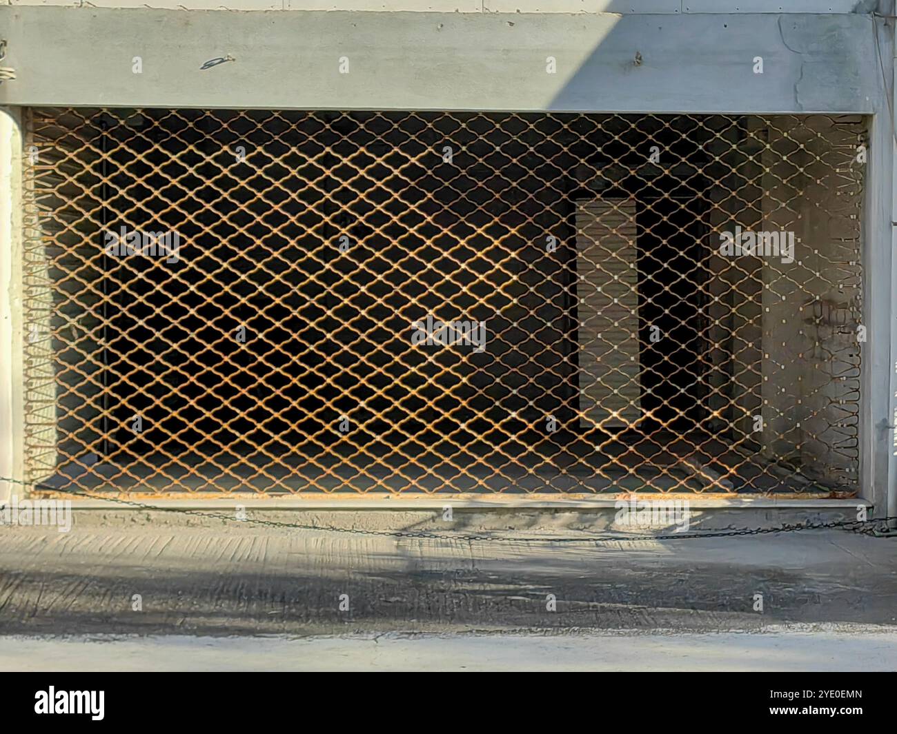 Metal Grid Fence: Der schattierte Kontrast des Closed Store in Brauntönen. Reflexion auf dem Dach von einem anderen Gebäude. Stockfoto