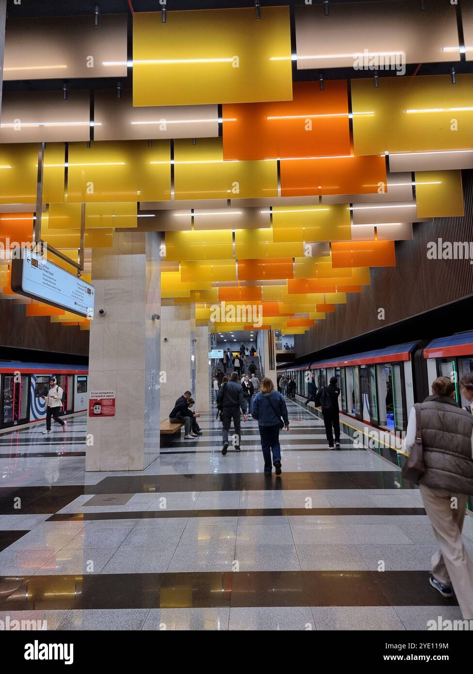 Innenraum der U-Bahn-Station Nowatorskaja an der Bolschaja Koltsewaya-Linie (BKL) der Moskauer U-Bahn, mit orangefarbenen und gelben Tafeln von der Decke Stockfoto
