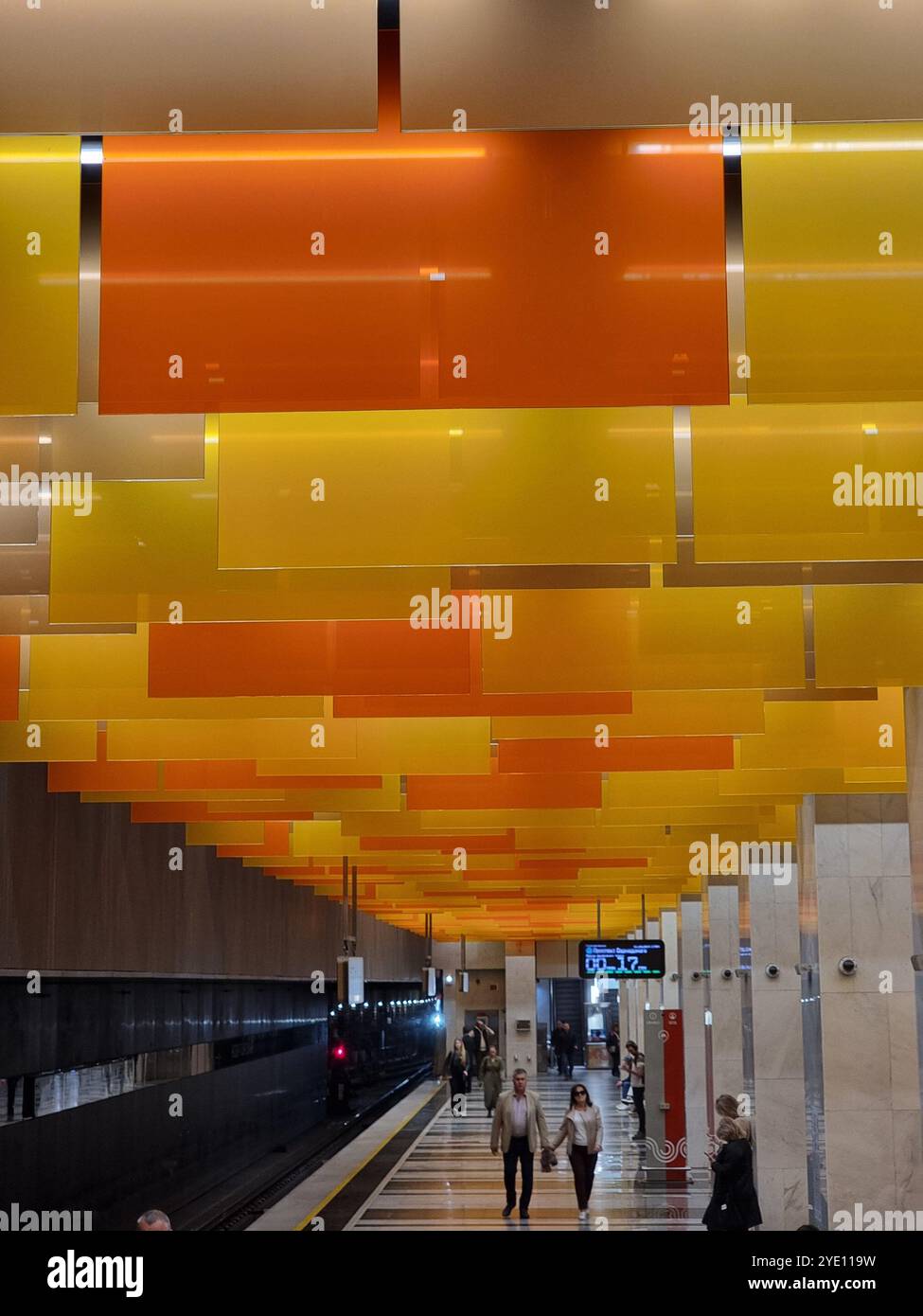 Innenraum der U-Bahn-Station Nowatorskaja an der Bolschaja Koltsewaya-Linie (BKL) der Moskauer U-Bahn, mit orangefarbenen und gelben Tafeln von der Decke Stockfoto