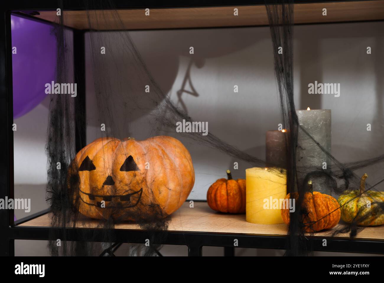 Halloween-Feier. Kürbis mit gruseligem Gesicht und Kerzen auf dem Regal Stockfoto