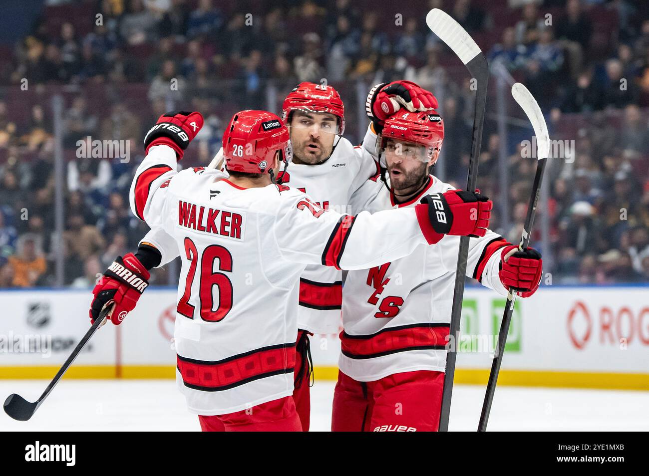 Carolina Hurricanes' William Carrier, center, celebrates after his goal with Sean Walker (26) and Shayne Gostisbehere (4) during first-period NHL hockey game action against the Vancouver Canucks in Vancouver, British Columbia, Monday, Oct. 28, 2024. (Ethan Cairns/The Canadian Press via AP) Stockfoto