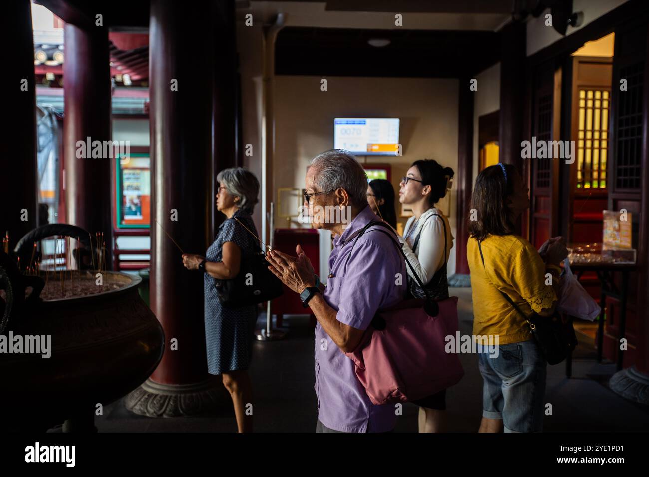 Chinesen, die einen dünnen Weihrauchstab halten, beten und um Segen bitten, im Buddha-Zahn-Reliquientempel. Chinatown. Singapur Stockfoto