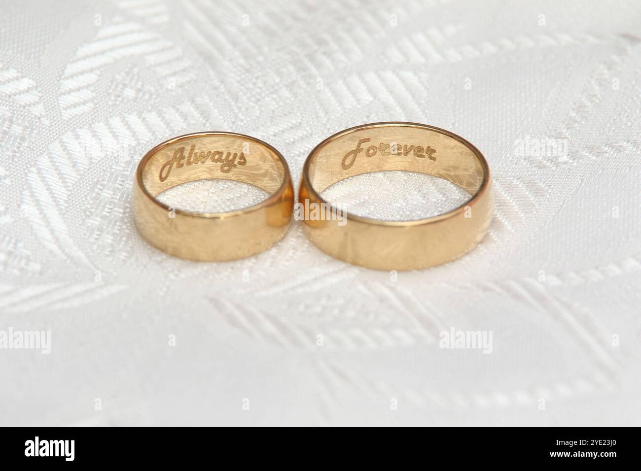 Goldene Eheringe auf weißer Tischdecke Stockfoto