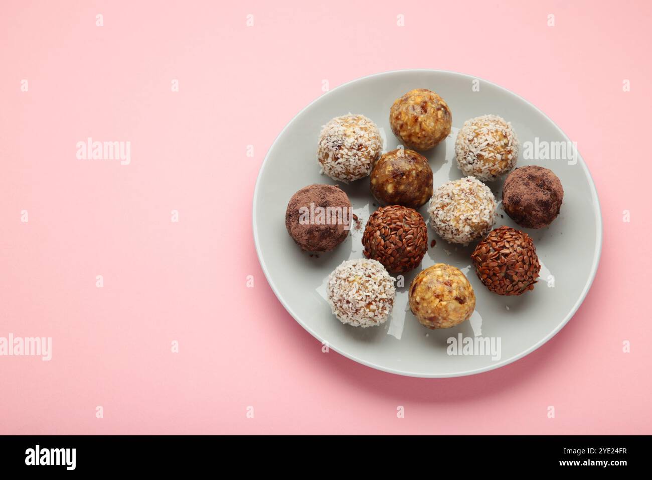 Gesunde hausgemachte Energiebälle mit Preiselbeeren, Nüssen, Datteln und Haferflocken auf rosa Hintergrund. Leerzeichen für Text. Draufsicht Stockfoto
