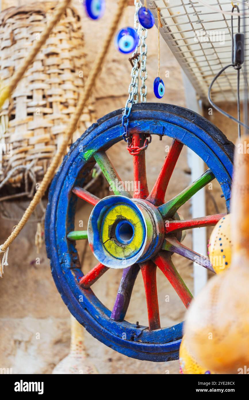 Ein lebendiges und farbenfrohes Holzrad mit unheilvollen bösen Augen, die daran hängen Stockfoto