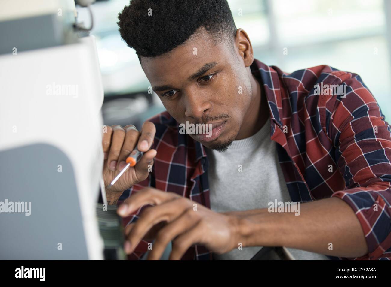 Junge Arbeitnehmer mit einem Schraubendreher für die Festsetzung der Drucker Stockfoto
