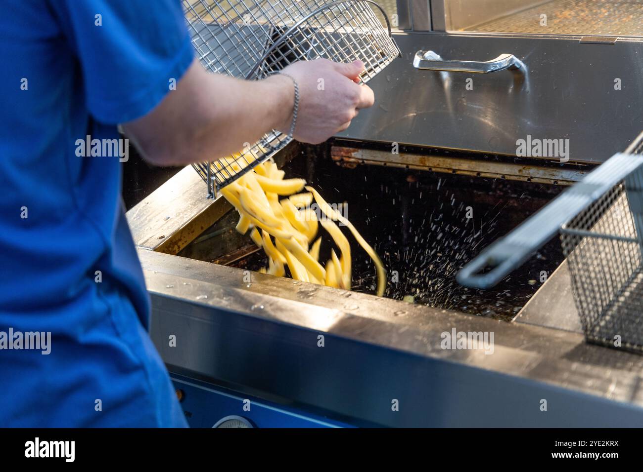 Person, die Chips in eine Fritteuse gießt Stockfoto